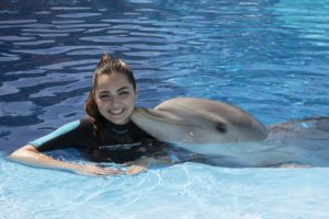 Chica en el agua con un delfín dándole un beso